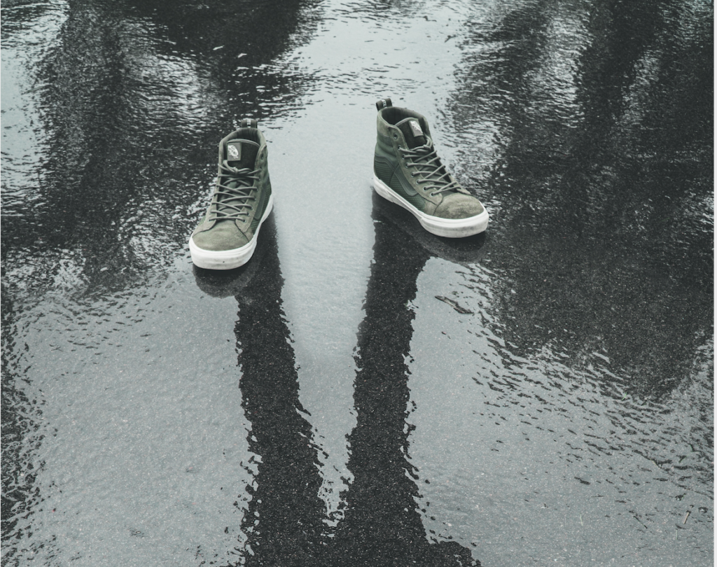 Paire de chaussures vides projetant l'ombre d'un homme sur le sol mouillé